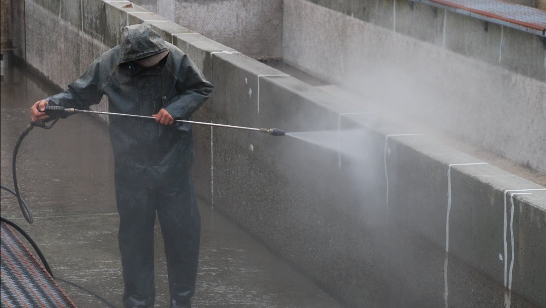 A patio being pressure washed to remove green moss and algae